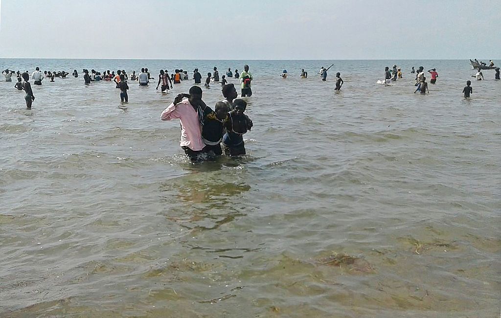 People help a man to come ashore from Lake Albert, on December 26, 2016 in Buliisa, after at least 30 Ugandan members of a village football team and their fans drowned when their boat capsized on Lake Albert during a party. Police officers working with local fishermen managed to rescue 15 of the revellers, who were heading from the village of Kaweibanda in the western Buliisa District to watch a friendly Christmas Day match in Hoima District, Rutagira said. / AFP / - (Photo credit should read -/AFP/Getty Images)