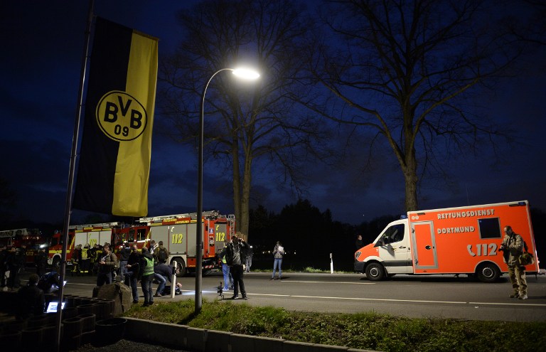 Police and firefighhters are seen near the site wher Borussia Dortmund's bus was damaged by an explosion some 10km away from the stadium prior to the UEFA Champions League 1st leg quarter-final football match BVB Borussia Dortmund v Monaco in Dortmund, western Germany on April 11, 2017. / AFP PHOTO / Sascha Schuermann